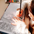 A young girl colors a black-and-white illustration in the "Child Counts to 20" activity book, using a pencil to fill in a detailed scene with a house, trees, and toys, with a set of colored pencils nearby.