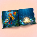 An open children's book displayed on a soft pink background, showing two illustrated underwater scenes: one with a child in a yellow raincoat and red boots holding a rainbow umbrella beside a duck, and one with glowing mushrooms and a bright circular light on the ocean floor.